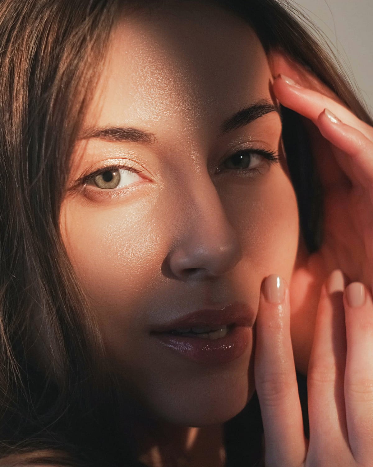 A woman resting her hand against her cheek in warm side light